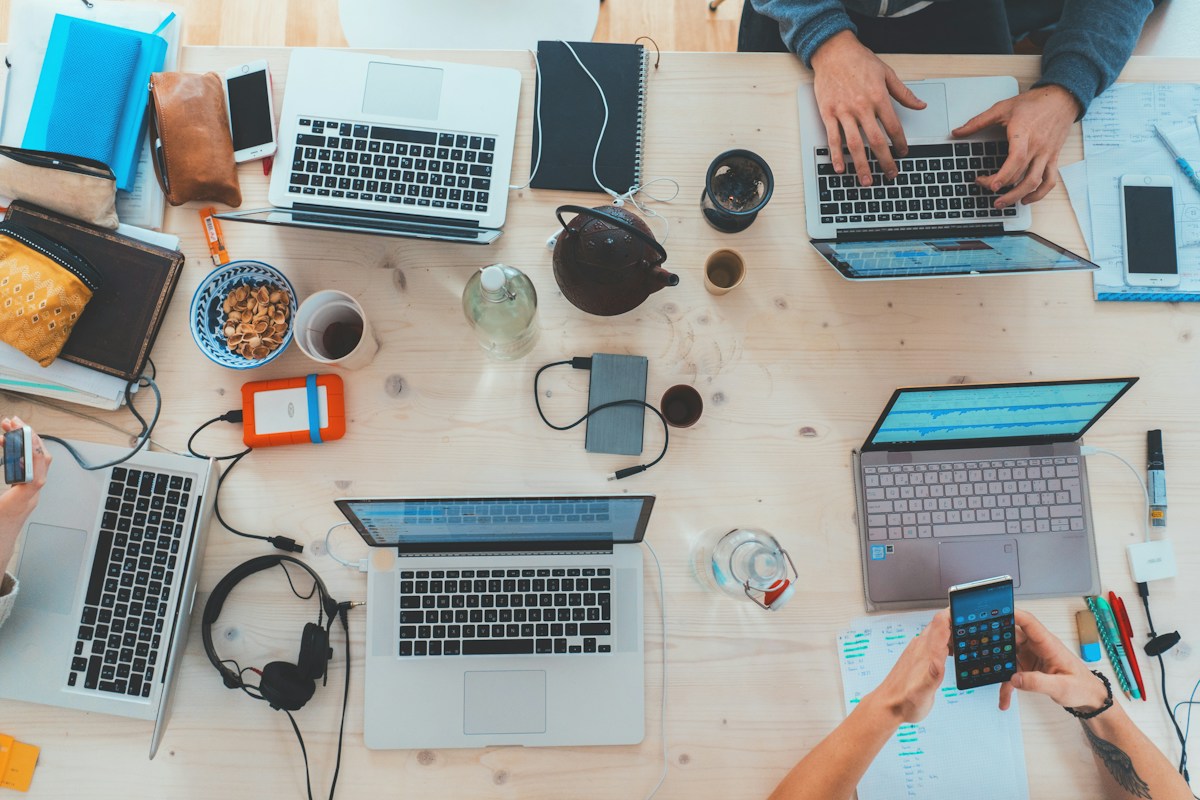 People collaborating with laptops on a shared desk — representative stock photograph