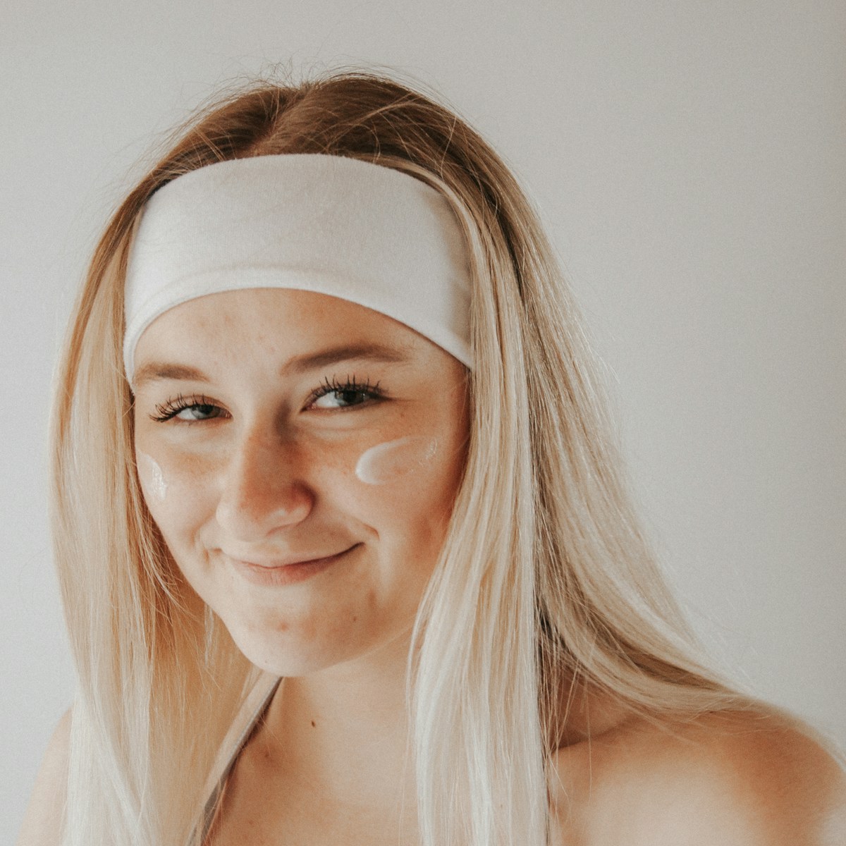 Woman with a headband and skincare cream — representative stock photograph